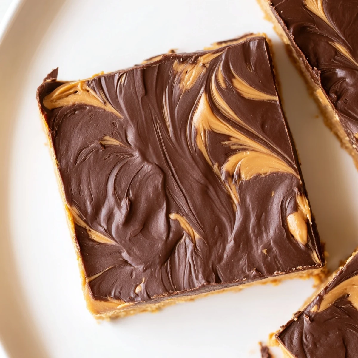 Decadent peanut butter bars arranged on a serving plate with glossy chocolate topping and crumbly texture