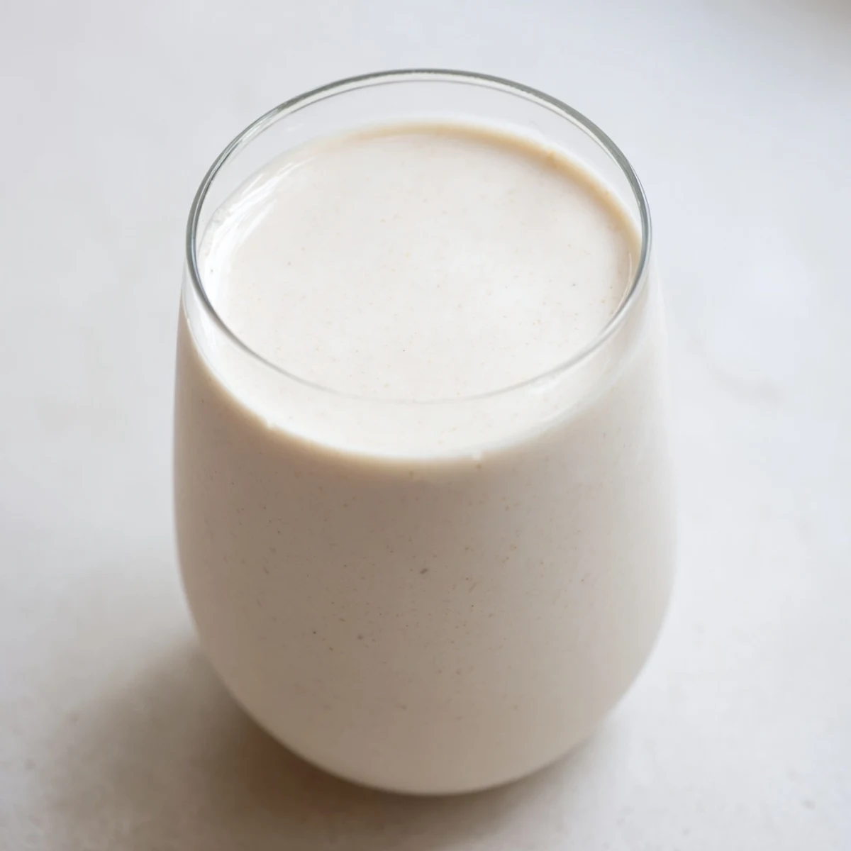 Creamy homemade almond milk poured into a glass jar with white almond pulp visible