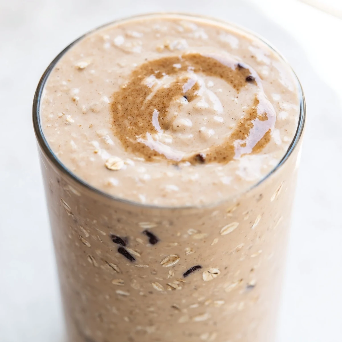Creamy oatmeal cookie dough protein smoothie topped with mini chocolate chips in a tall glass