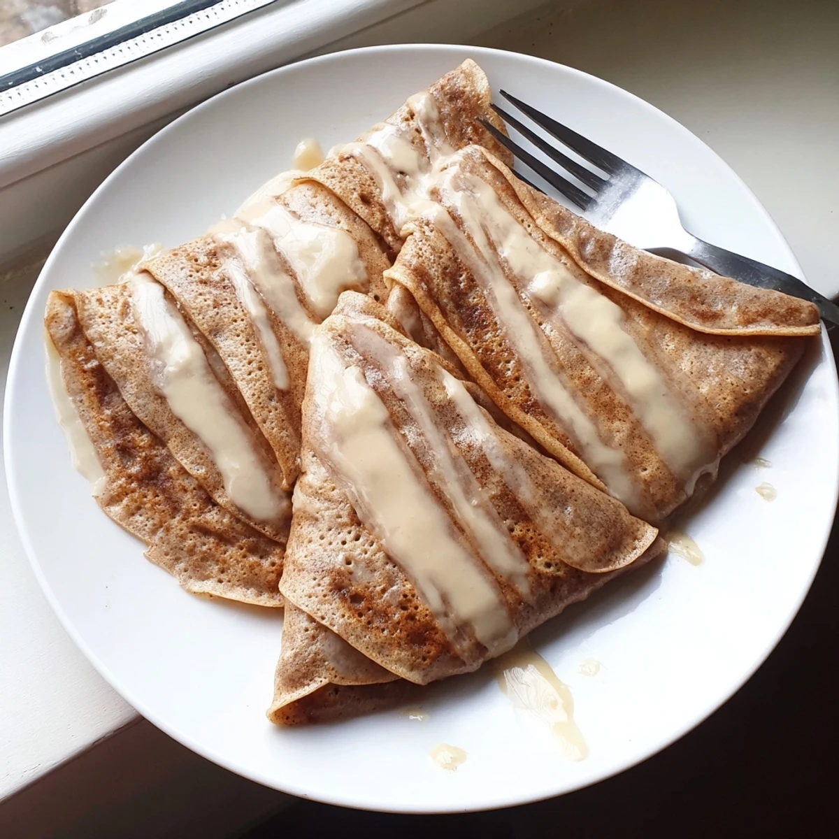Cinnamon roll protein crepes rolled with spiced filling and topped with cream cheese glaze