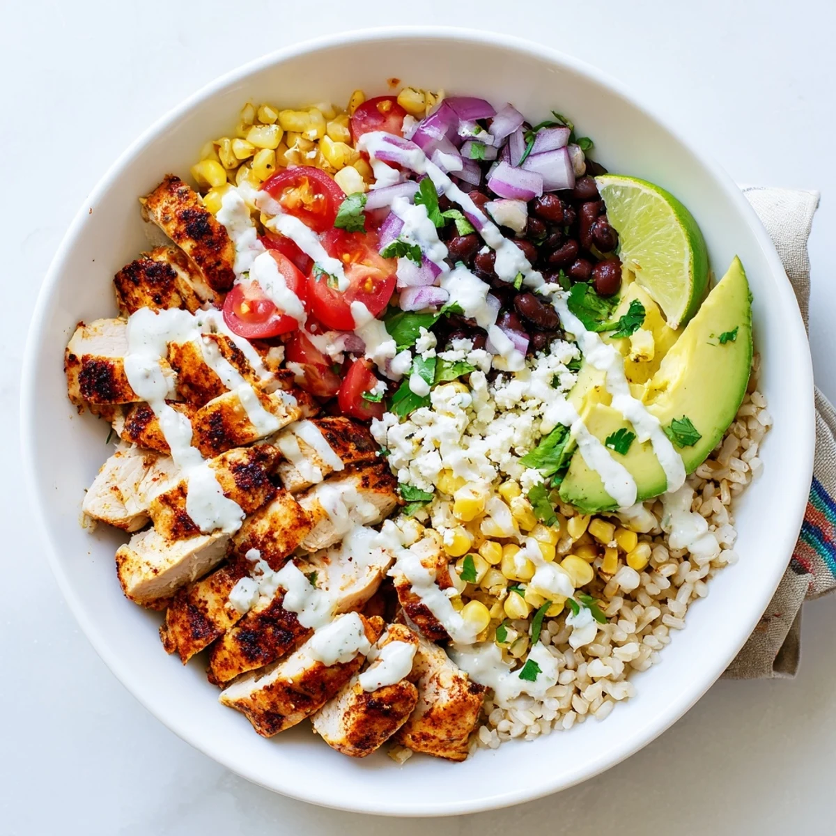 Colorful healthy street corn chicken bowl drizzled with tangy cotija yogurt sauce