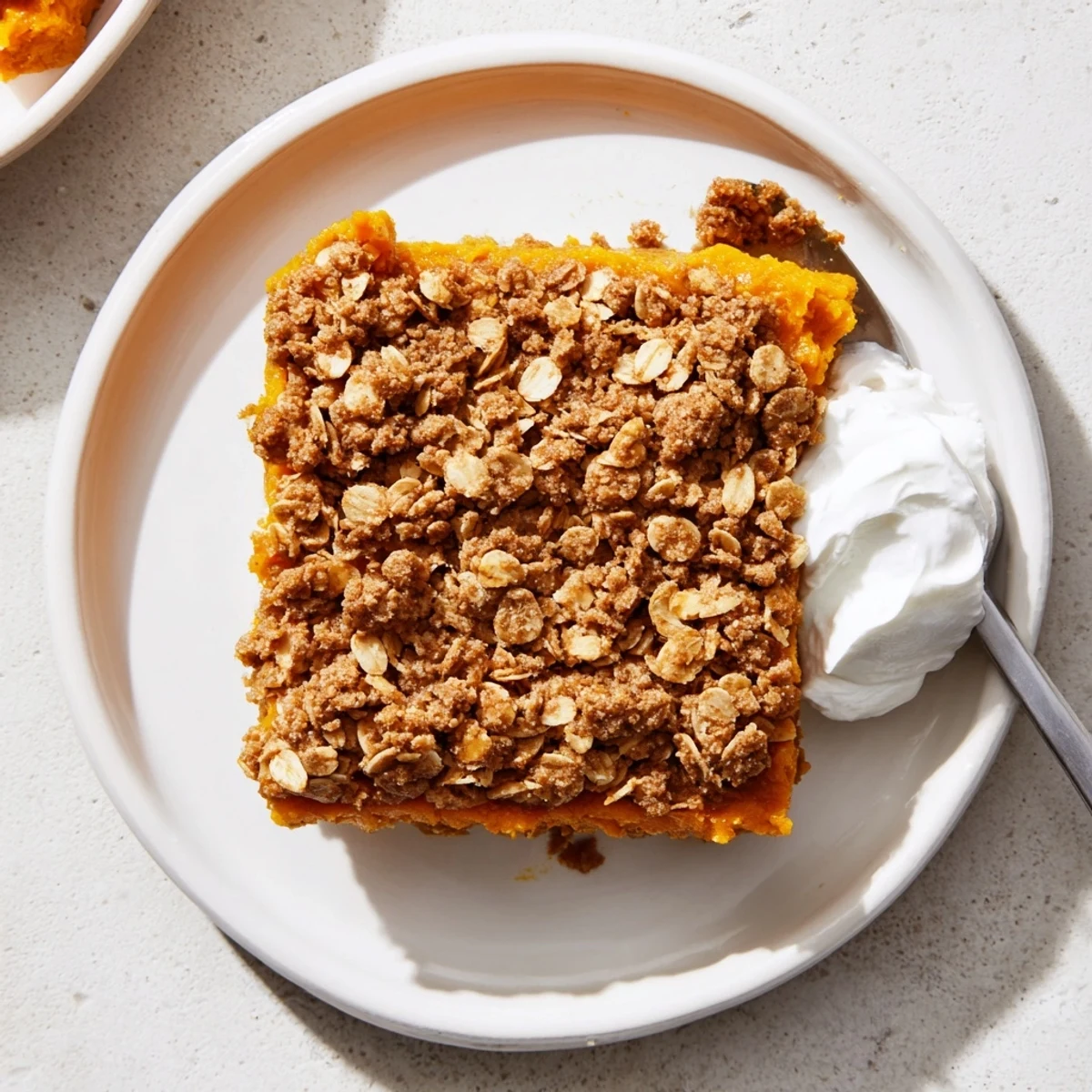 Warm pumpkin pie crisp scooped into a bowl with whipped cream topping