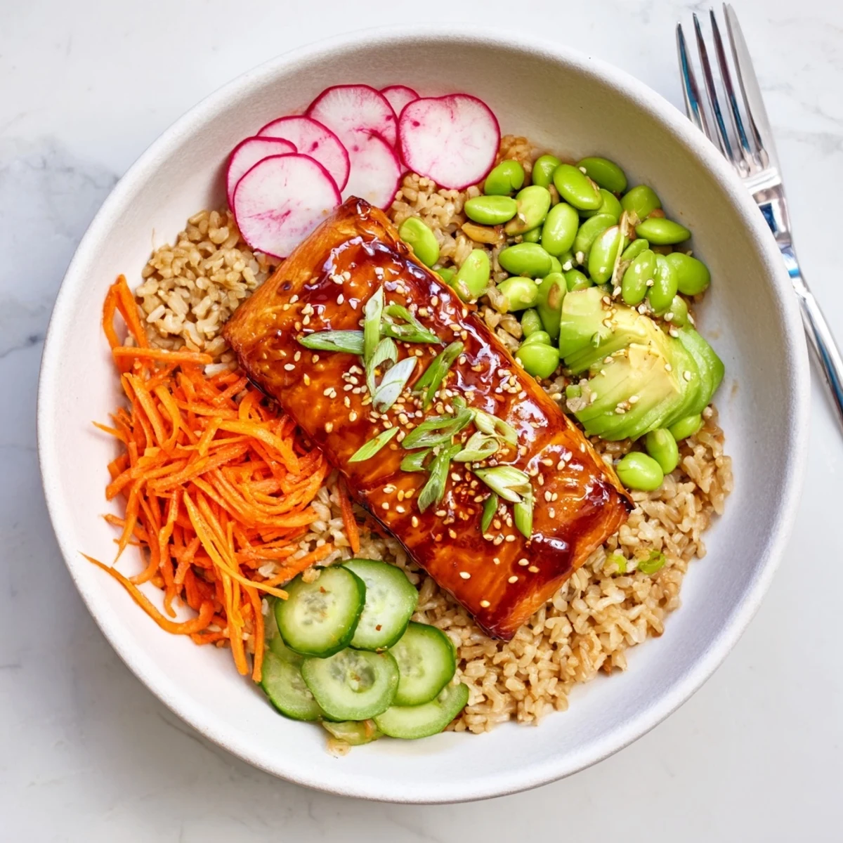 Broiled Asian salmon grain bowl drizzled with tangy dressing and scattered with fresh scallions