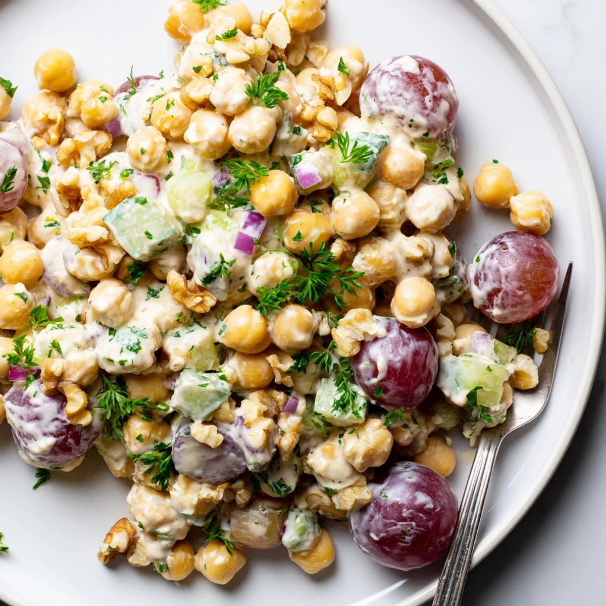 Bowl of vegan chicken salad studded with grapes walnuts and fresh parsley
