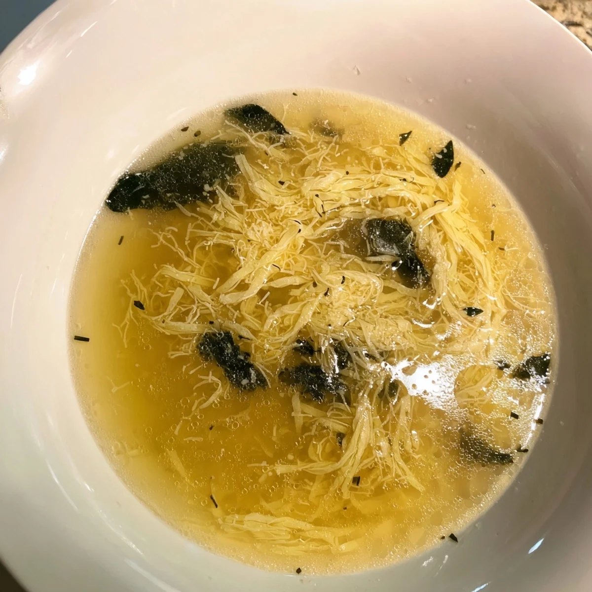 Stracciatella Soup topped with Parmesan cheese in a golden savory broth