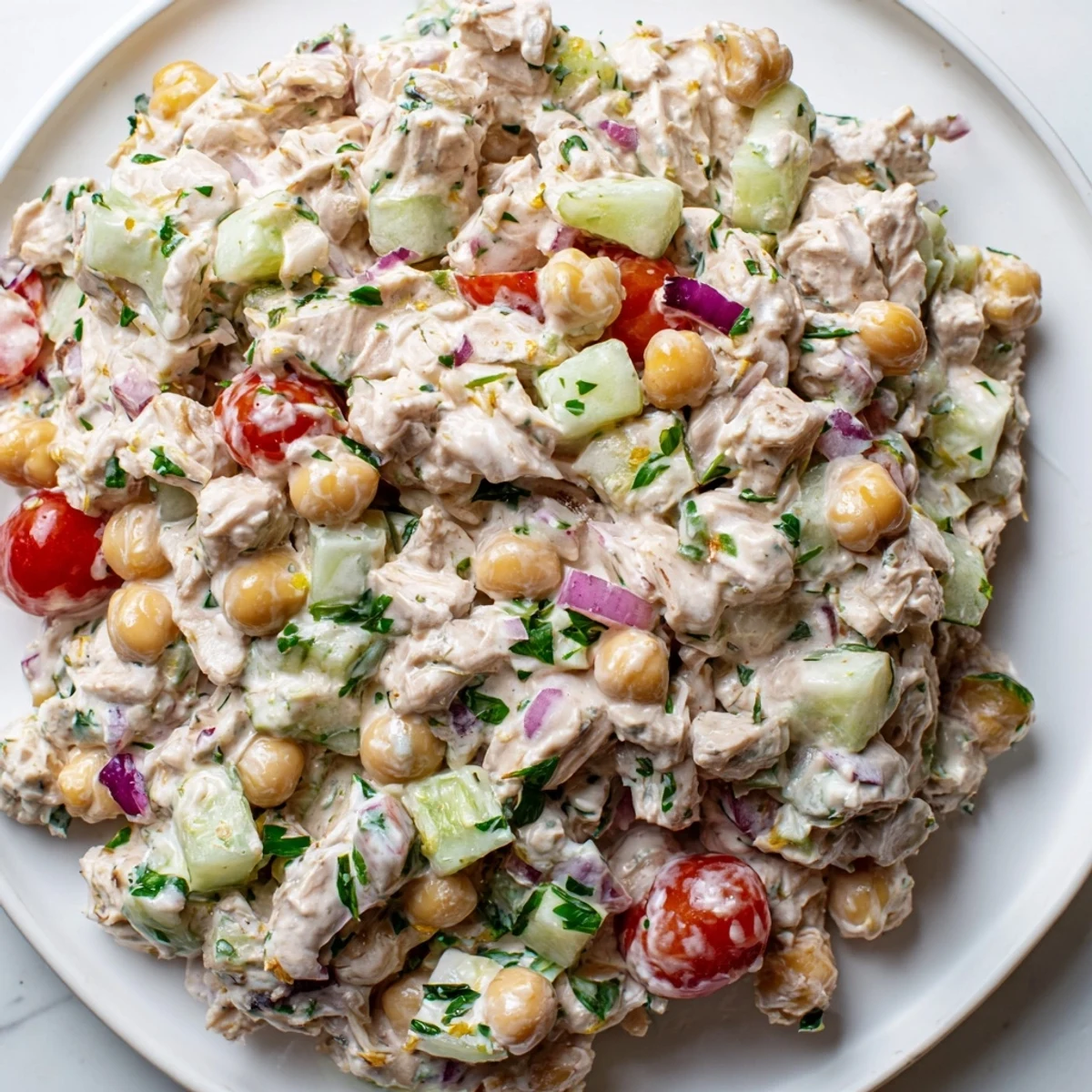 Creamy tuna chickpea cucumber salad served in a rustic bowl with fresh parsley garnish
