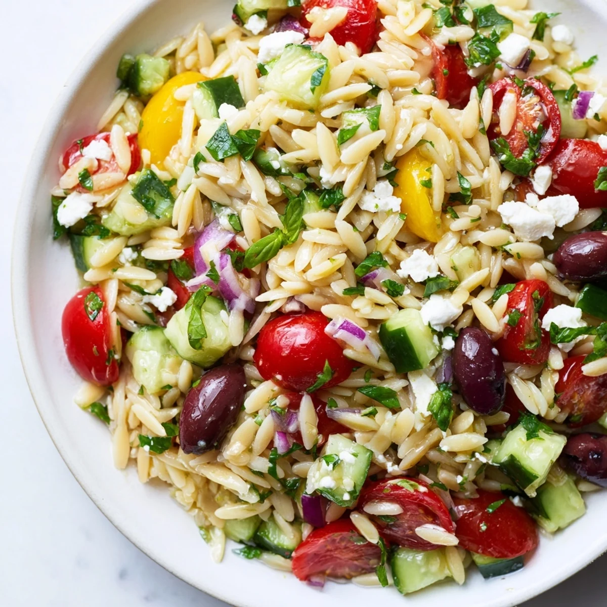 Colorful Mediterranean Orzo Pasta Salad in a rustic bowl with cherry tomatoes and crumbled feta