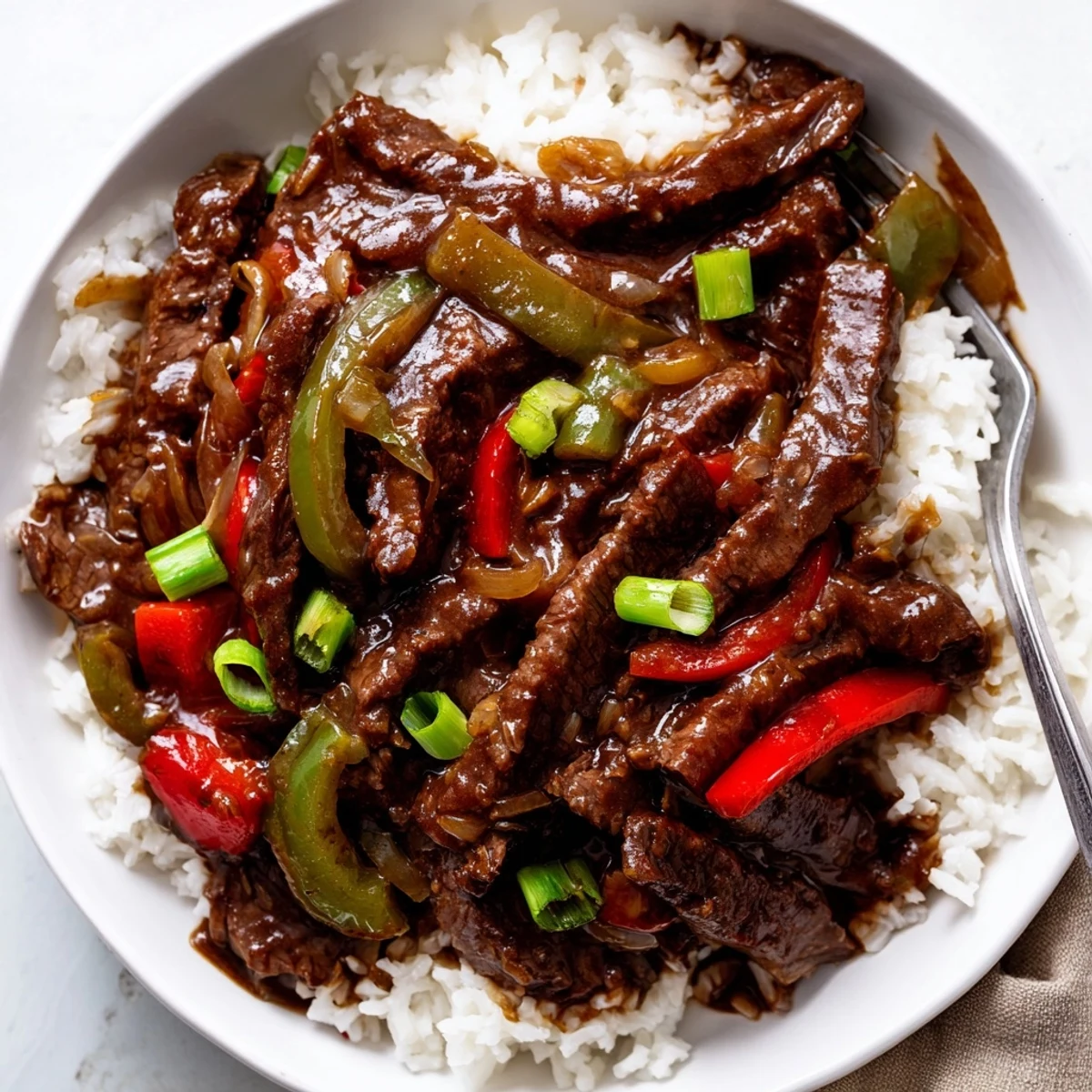 Hearty Slow Cooker Pepper Steak garnished with green onions and served in a rustic bowl