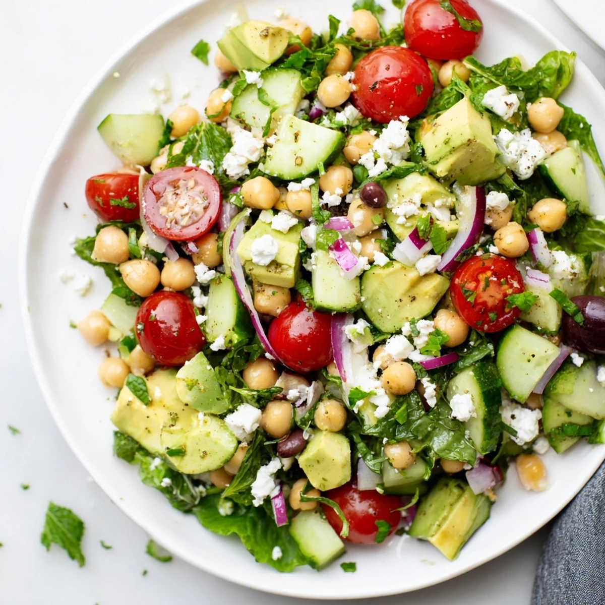 Golden olive oil drizzled over chickpea feta avocado salad on a sunny plate