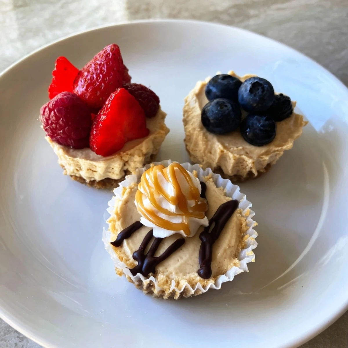 Creamy mini cheesecakes topped with fresh berries on a rustic white plate