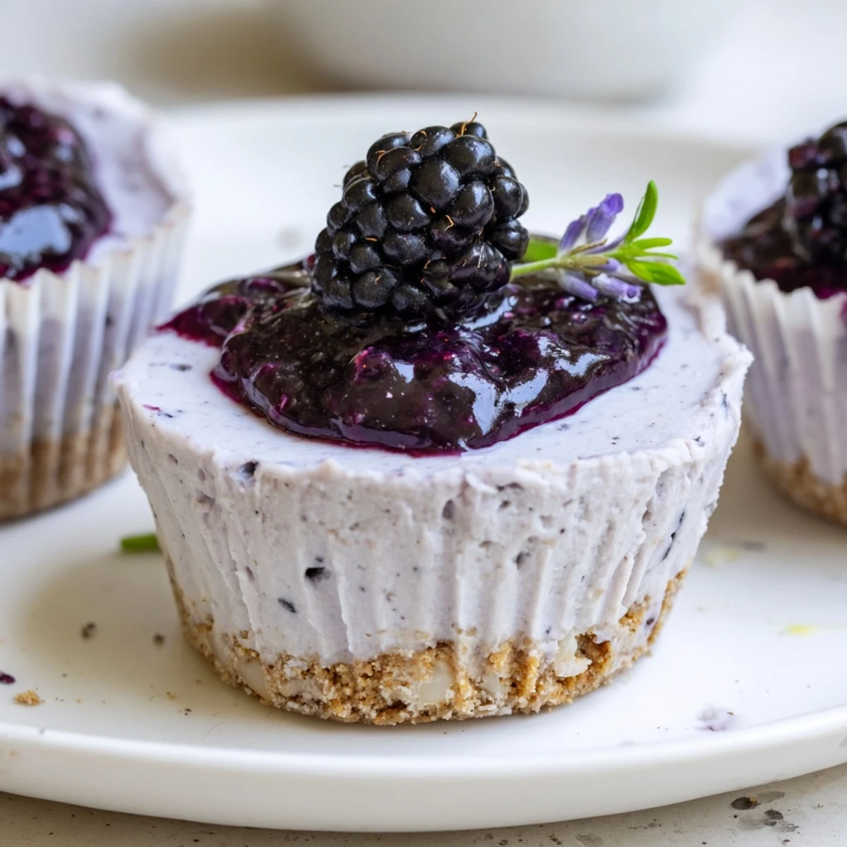 Creamy No Bake Mini Blackberry Lavender Cheesecakes topped with glossy, jewel-toned berry sauce