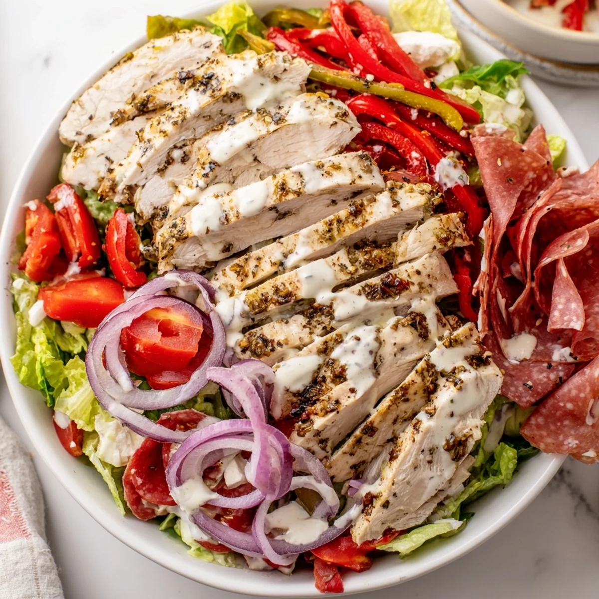 Italian Grinder Chicken Salad layered with deli meats, cheese, and crisp vegetables on a rustic plate