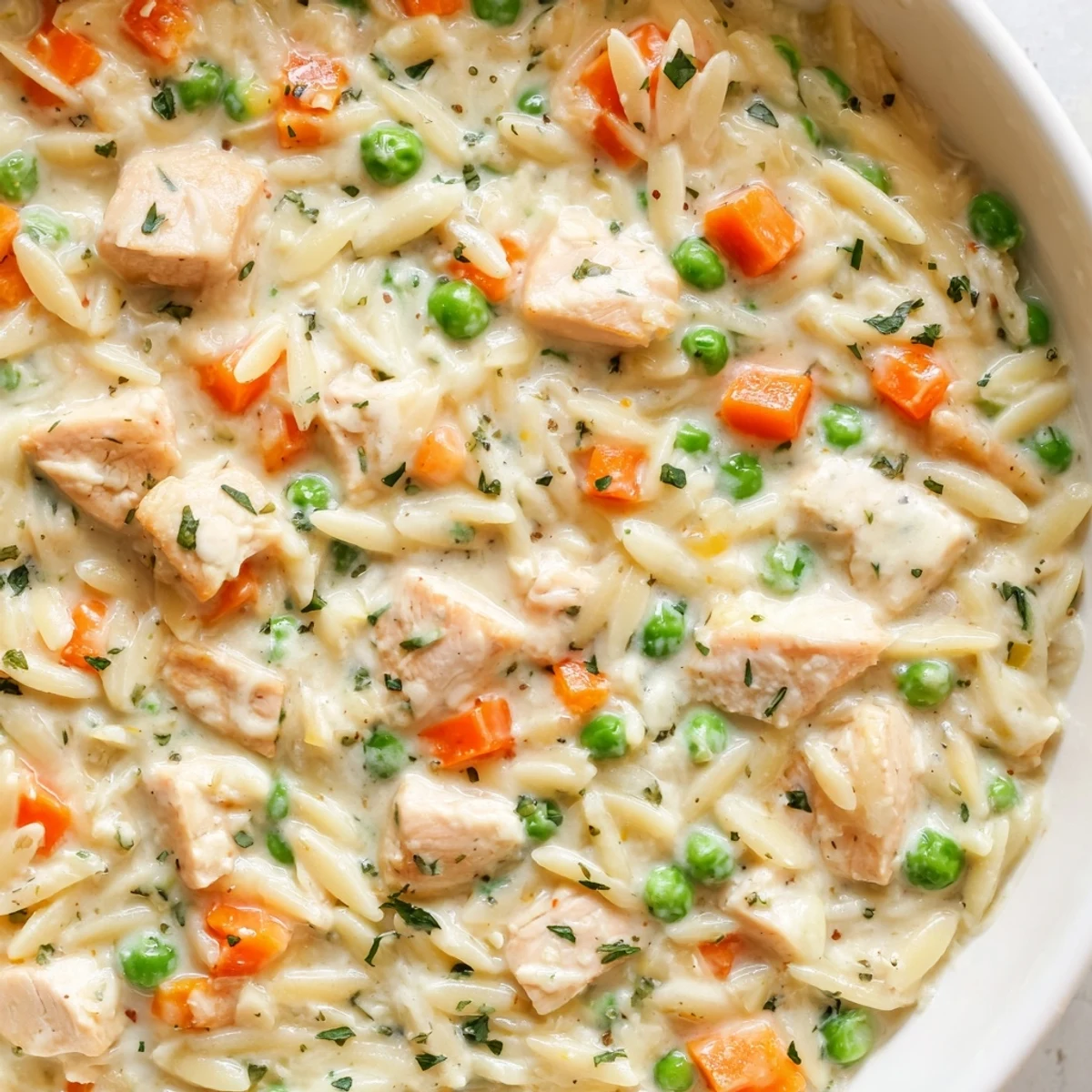 Golden creamy chicken pot pie orzo with tender carrots and peas in a rich sauce