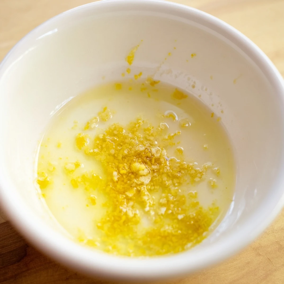 Golden lemon vinaigrette dressing recipe in a glass jar with fresh herbs.  