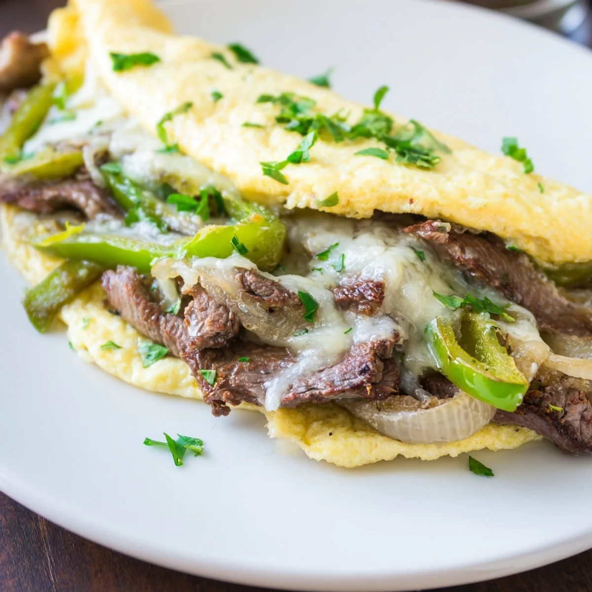 Golden Philly cheesesteak omelette filled with savory steak, peppers, and melted provolone.