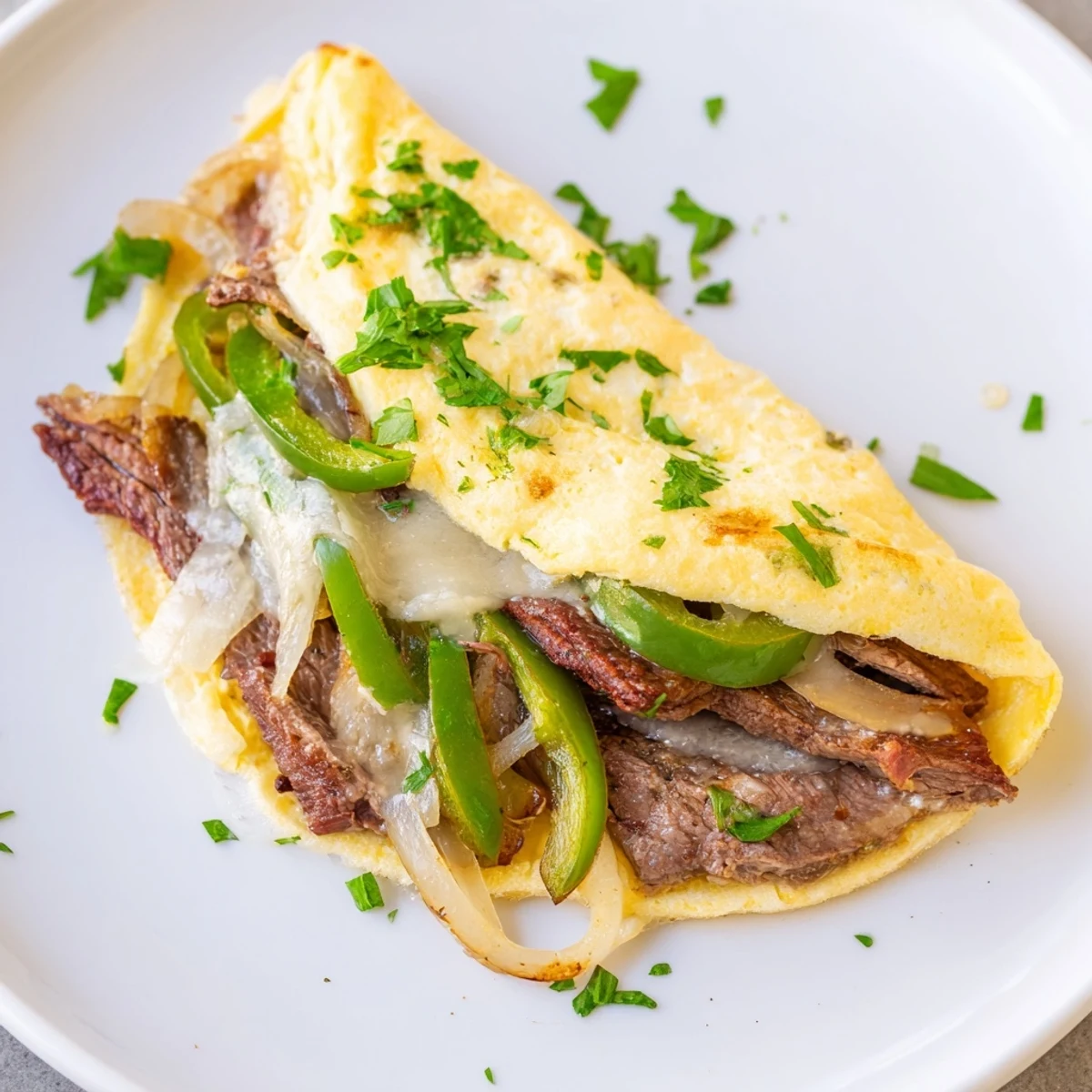 Fluffy omelette stuffed with tender beef, onions, and gooey cheese for breakfast.