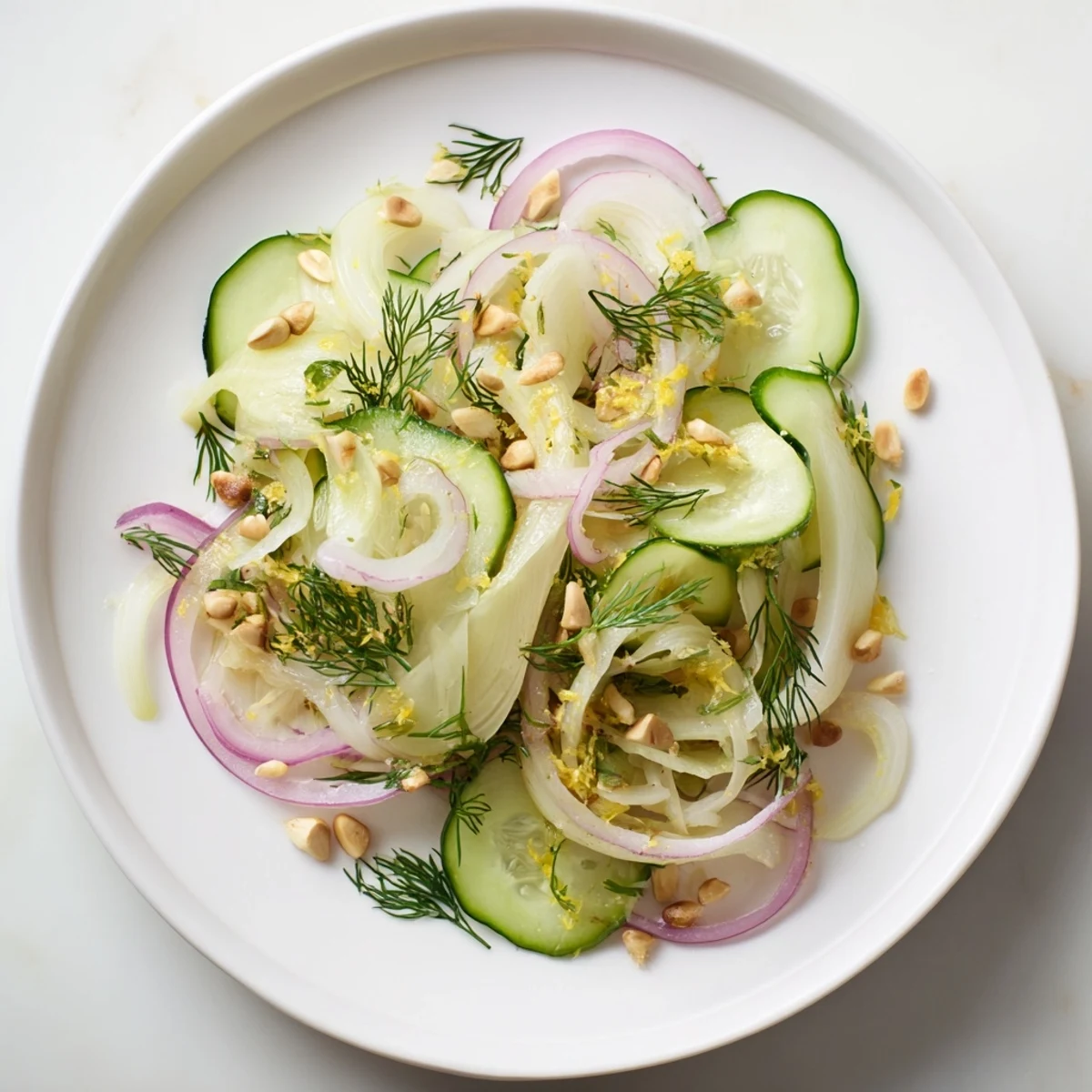 Golden pine nuts garnish this colorful crisp fennel cucumber salad with red onion and dill