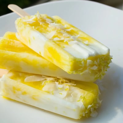 Creamy vegan Pineapple Coconut Lime Popsicles garnished with fresh lime zest and shredded coconut